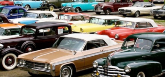 Esta imagen muestra una gran colección de coches clásicos de varios colores y modelos estacionados en un área al aire libre. Hay coches de color rojo, azul, verde, dorado y blanco.