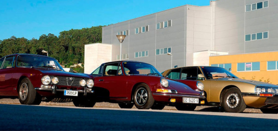 En esta imagen, hay tres coches clásicos estacionados uno al lado del otro. El coche de la izquierda es de color rojo oscuro, el del medio es de color rojo y el de la derecha es de color dorado.
