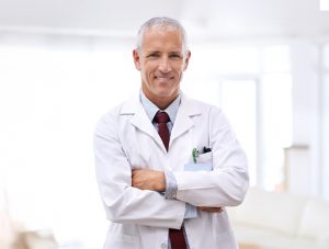 Médico con bata sonriendo con los brazos cruzados
